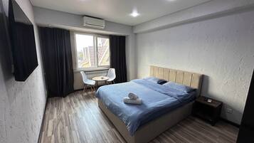 Un dormitorio con cama, una mesita, dos sillas, un equipo de aire acondicionado y una ventana.