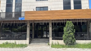 A building with a modern entrance, a wooden overhang, and a sign indicating a location. - Gatsby Vostok 5 (Bishkek)