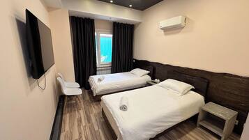 A hotel room with two beds, a TV, a ceiling light, and an air conditioner.