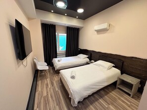 A hotel room with two beds, a TV, a ceiling light, and an air conditioner. - Gatsby Vostok 5 (Bishkek)