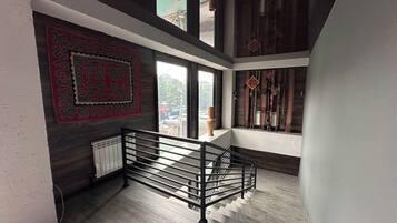 Un interior moderno con una escalera, un tapiz con estampado y vistas a través de una ventana.