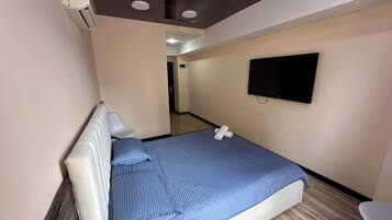 Quarto de hotel com cama, televisão e uma cadeira.