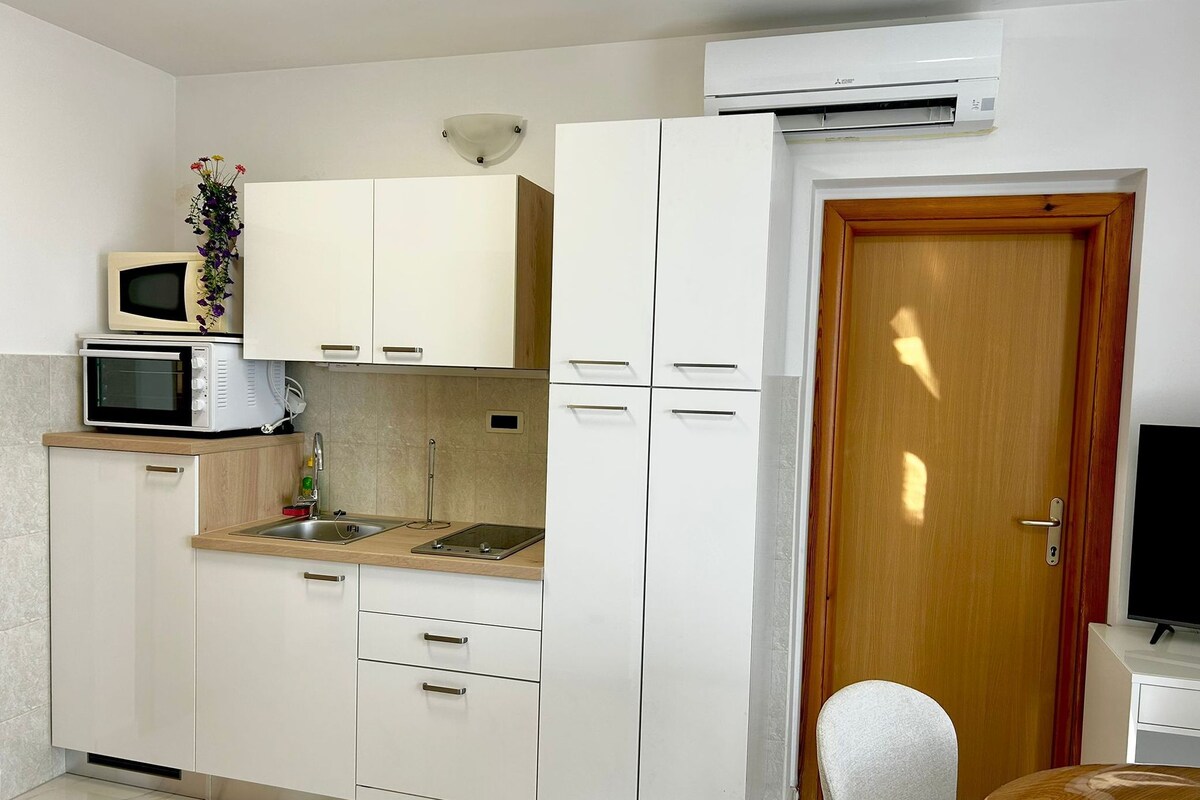 A compact kitchen with white cabinets, a microwave, a toaster, and a sink.