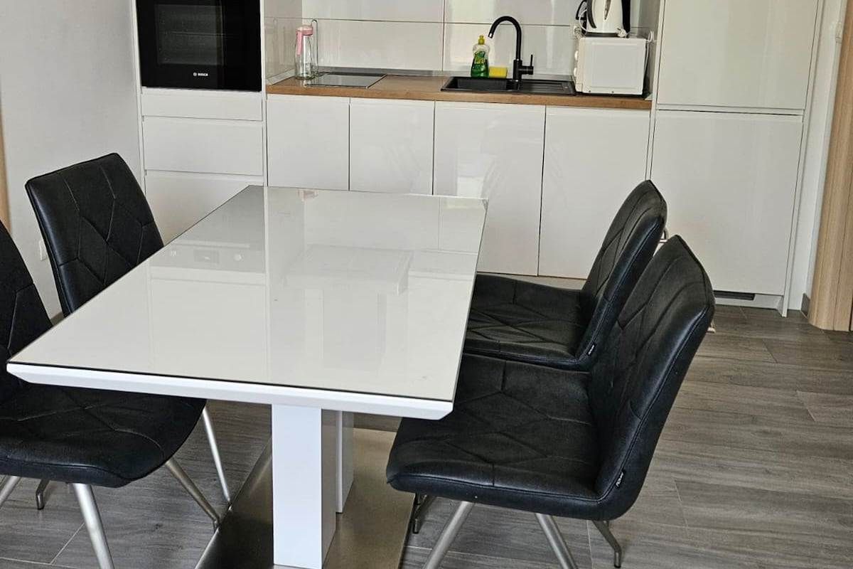 A modern kitchen with white cabinets, a black stove, and a white countertop.