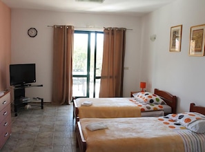 A hotel room with two beds, a television, a desk, and a window with curtains. - Apartments Anton & Blanka (Orebic)