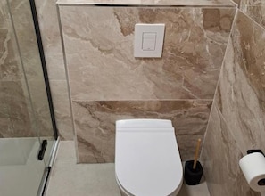 A bathroom with a toilet, a hand dryer, and a toilet paper holder. - Apartments Anton & Blanka (Orebic)