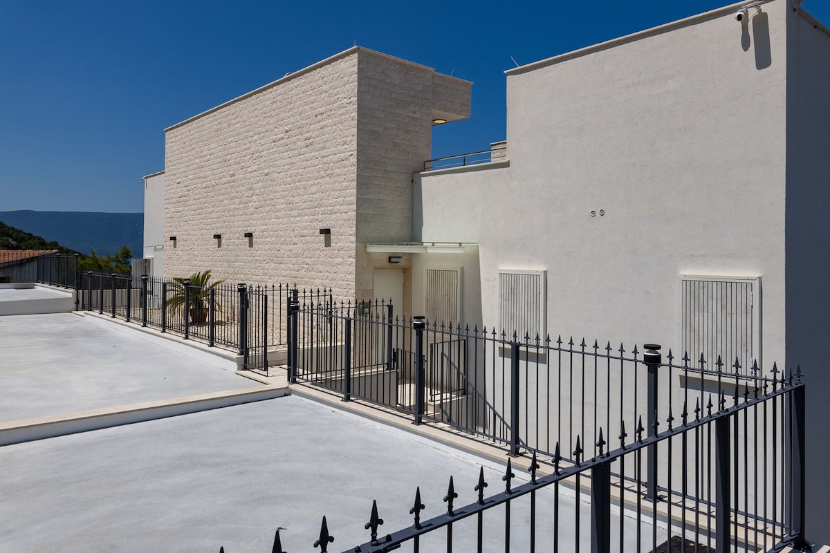 A building with a flat roof, a gated entrance, and a clear view of the sea.