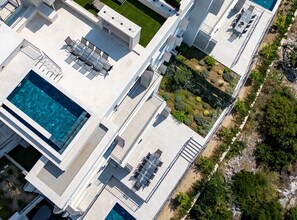 A modern building with a rooftop pool, outdoor seating, and a landscaped garden.
