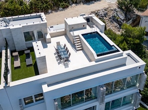 A modern building with a rooftop pool, outdoor seating, and a view of the surrounding landscape.