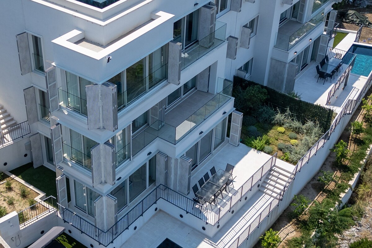 A multi-story residential building with balconies, a rooftop pool, and a landscaped garden.