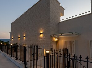 A modern building with a stone facade, a metal fence, and exterior lighting. - Villas Mr&mrs Smith (Slivno)