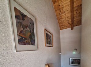 A room with two framed paintings on the wall, a wooden ceiling, and a light switch. - Villa Lili (Murter-Kornati)