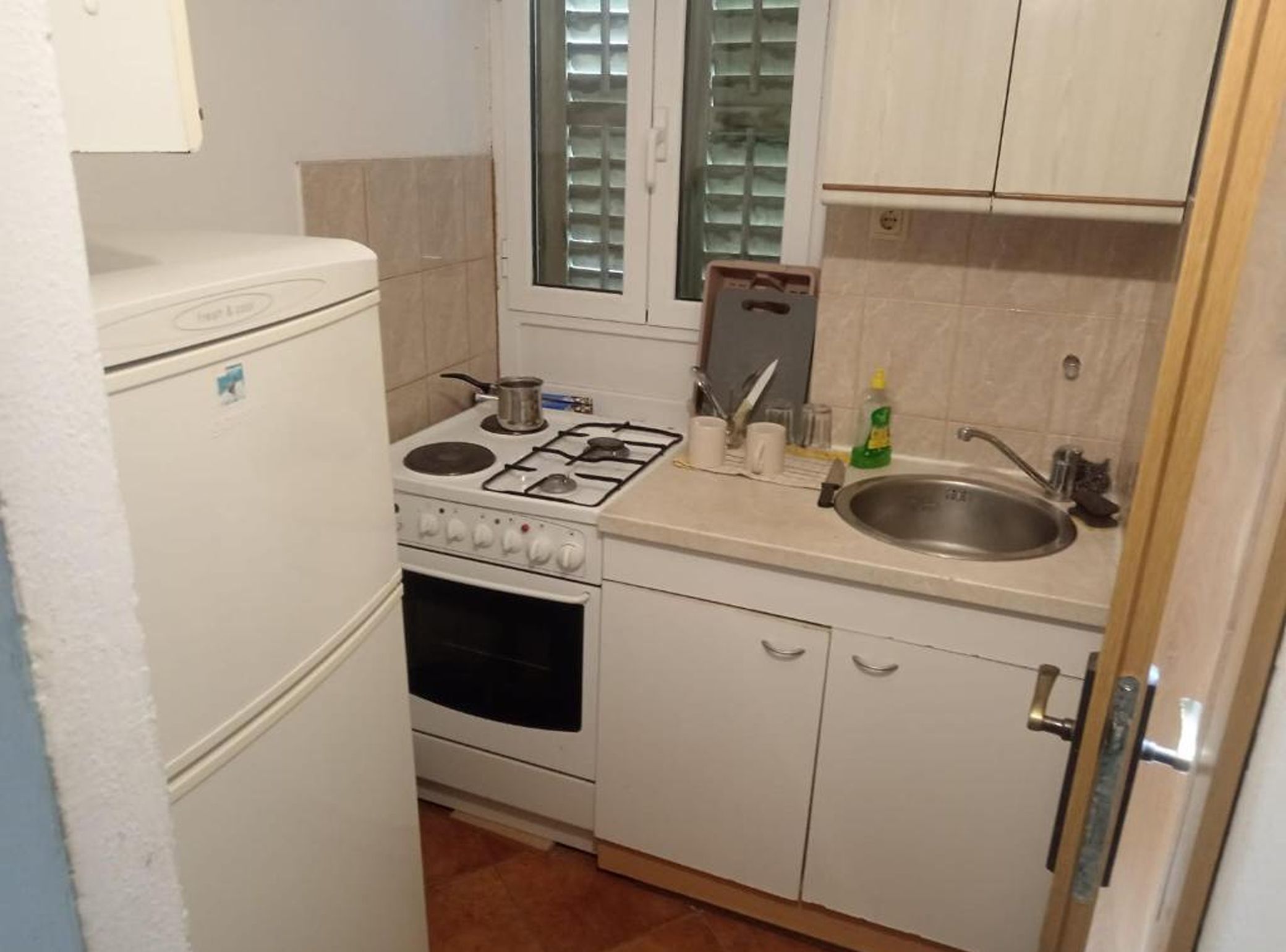 Una cocina compacta con estufa, horno, pileta y placares.