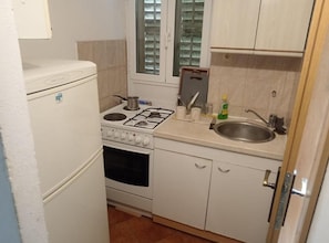 Cozinha compacta com fogão, forno, pia e armários.