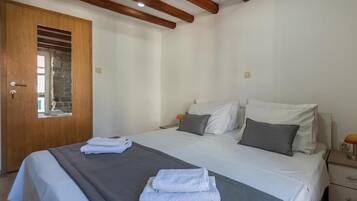 Un dormitorio con una cama, una puerta de madera y una mesita de noche con una lámpara.