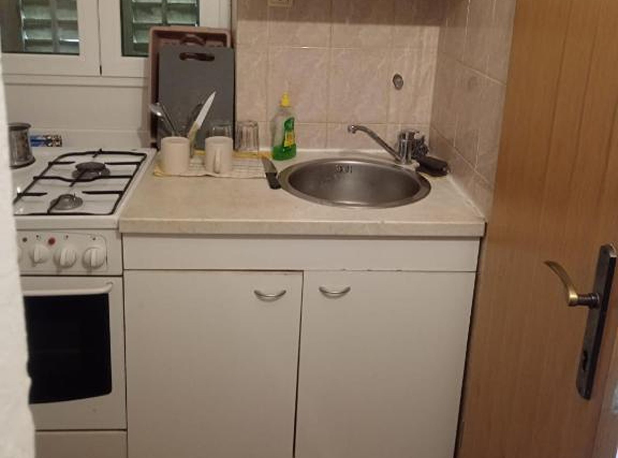 Cozinha compacta com fogão a gás, pia e armários.