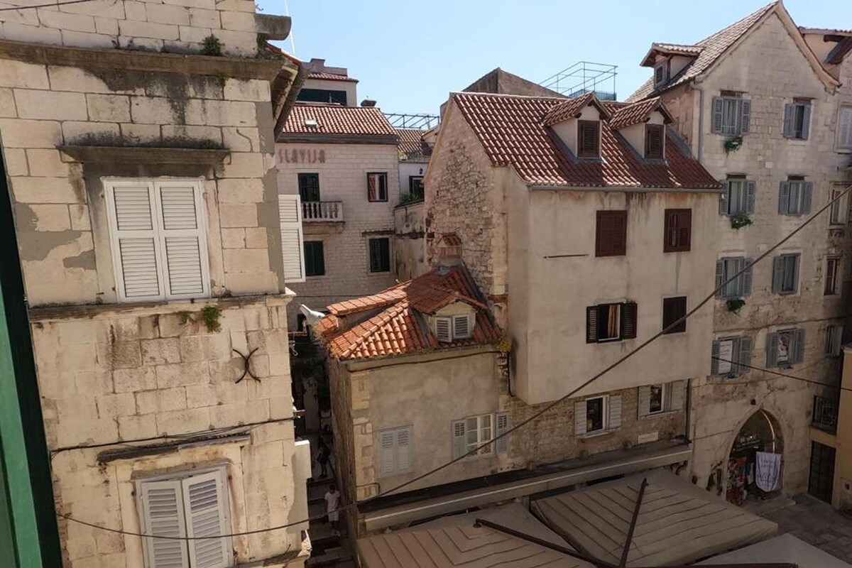 Uma rua estreita com edifícios tradicionais, alguns com varandas e janelas aparentes.