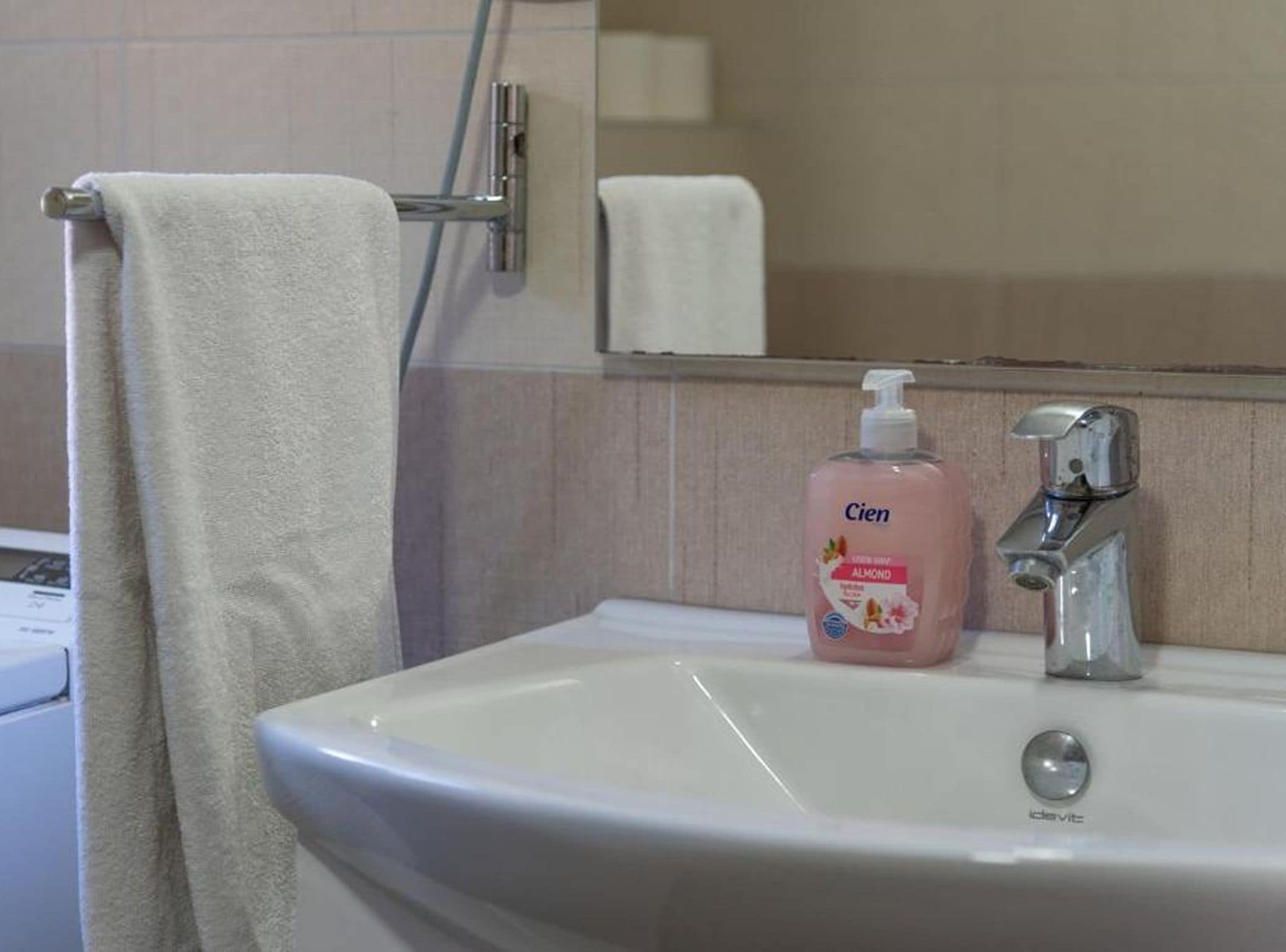A bathroom with a white sink, a mirror, and a towel hanging on a rack.