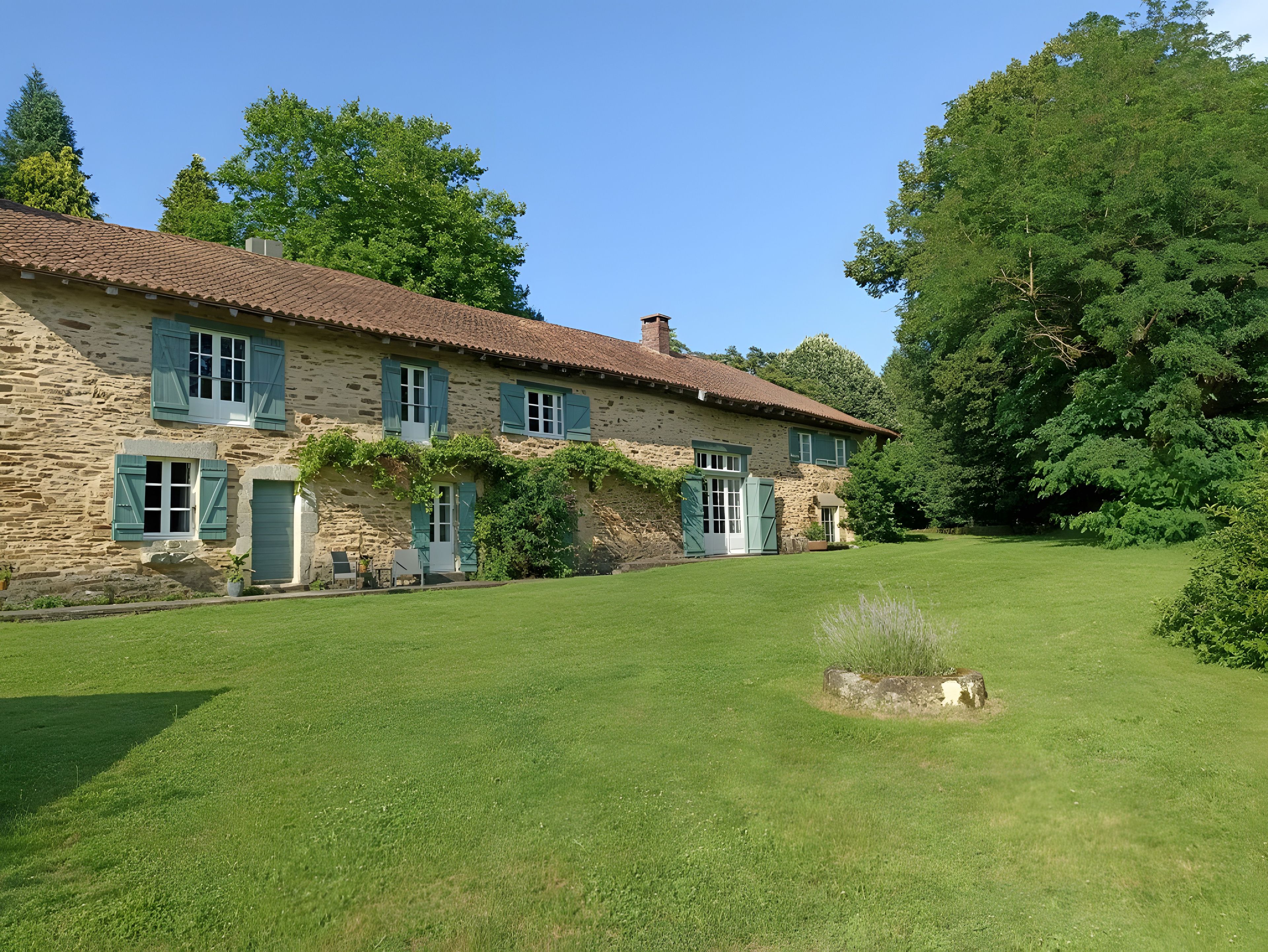 Un bâtiment en pierre doté de nombreuses fenêtres et d’une pelouse bien entretenue.