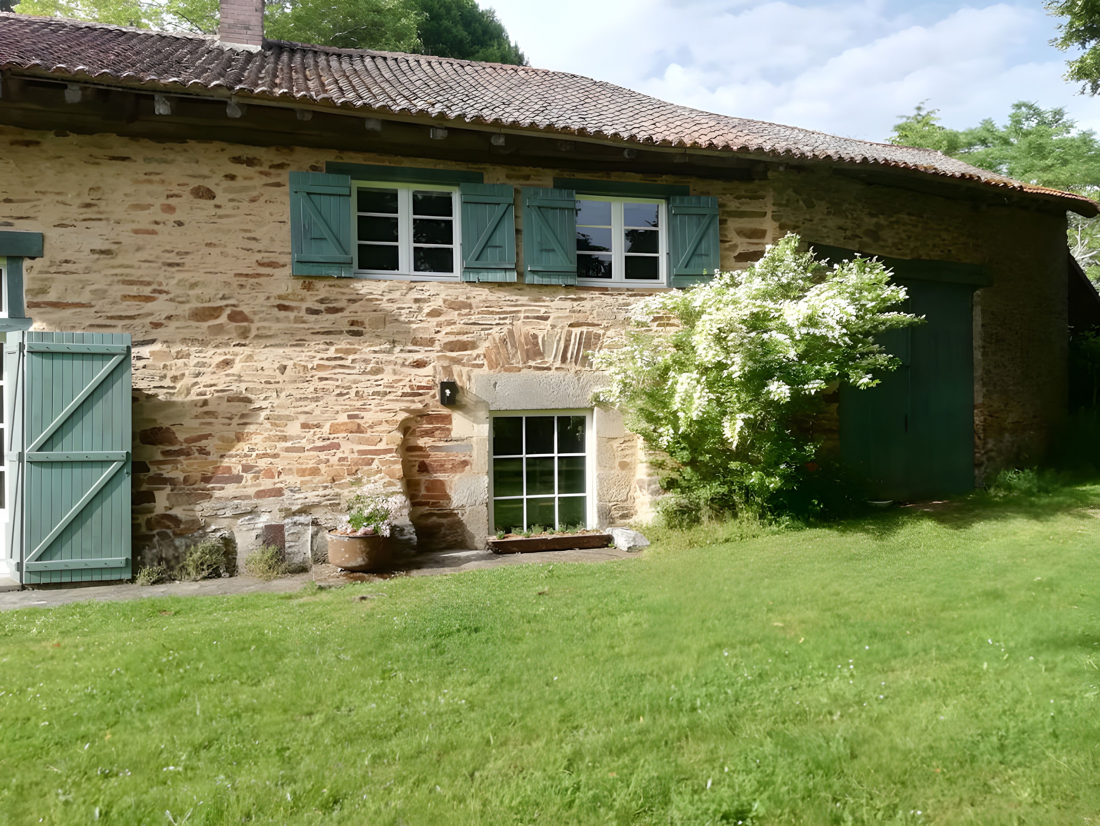 Une maison en pierre avec un toit en tuiles, des volets verts et un petit jardin.
