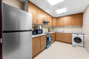 A modern kitchen with stainless steel appliances, wooden cabinets, and a built-in washing machine. - StayShort - Elegant 2 bedroom that sleeps 4! (JLT)