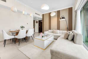 A modern living room with a sofa, coffee table, and dining area with chairs. - StayShort - Elegant 2 bedroom that sleeps 4! (JLT)