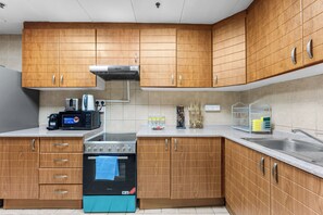 Eine moderne Küche mit Holzausbau, einem Backofen, einer Mikrowelle und einem Edelstahlspülbecken.