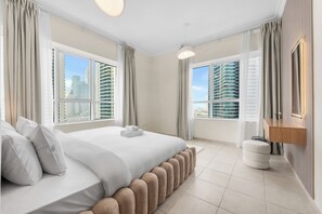 Ett modernt hotellrum med en stor säng, två fönster, utsikt över staden och ett litet badrum.