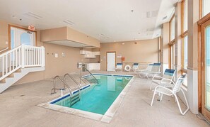A swimming pool with a sun terrace, lounge chairs, and an exit sign. - Luxury Oceanfront Condo Located Mid Town (Ocean City)