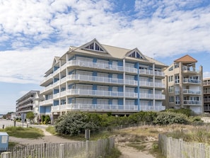A multi-story hotel with balconies, located near a beach. - Luxury Oceanfront Condo Located Mid Town (Ocean City)