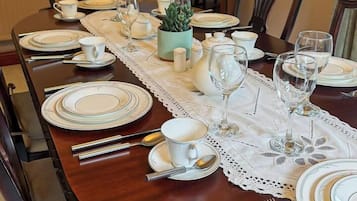 A dining table set for six with white plates, silverware, and clear glassware.
