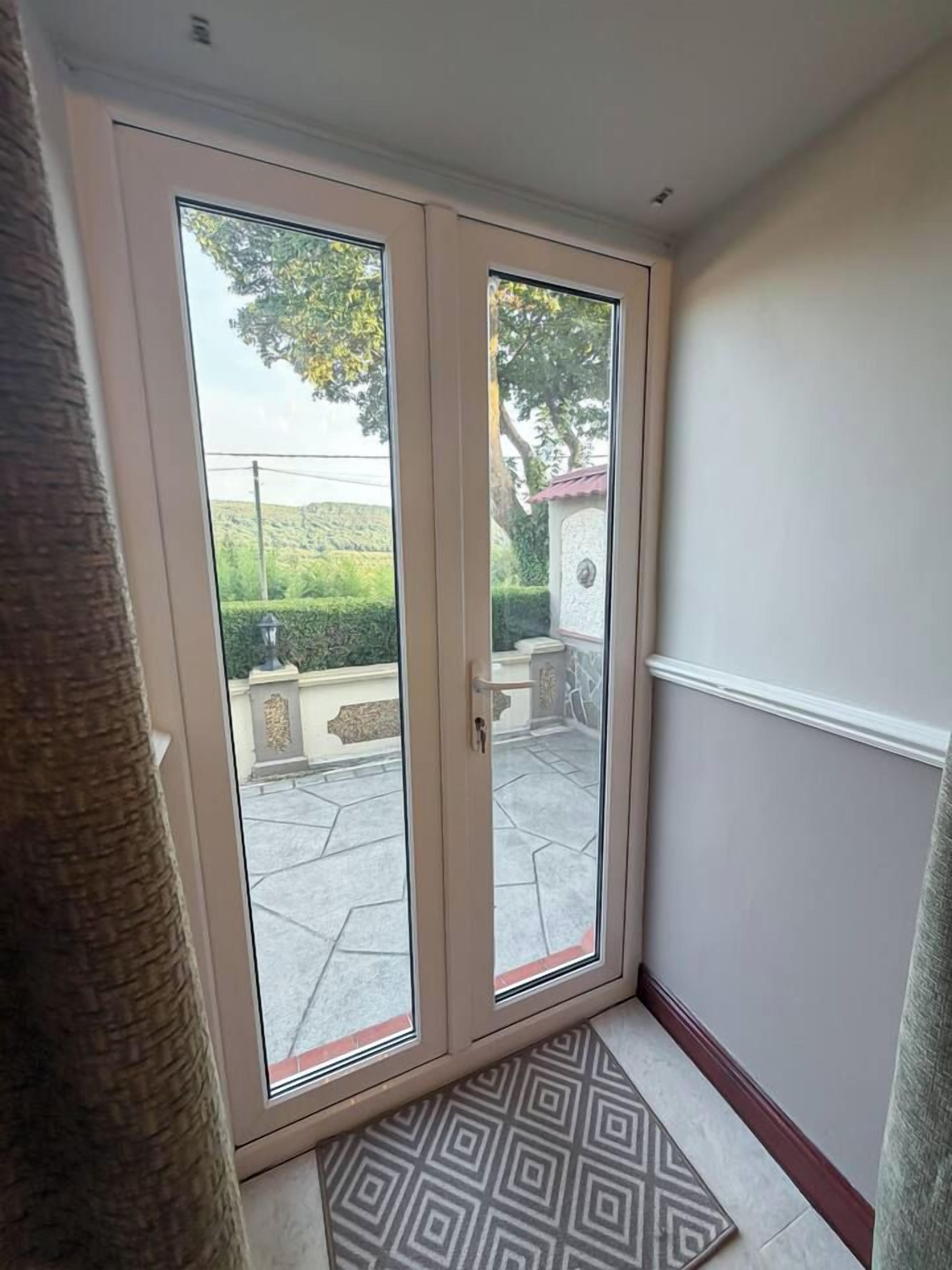 Puerta corrediza de vidrio que da a un patio al aire libre con un suelo de diseño y una pared de piedra.