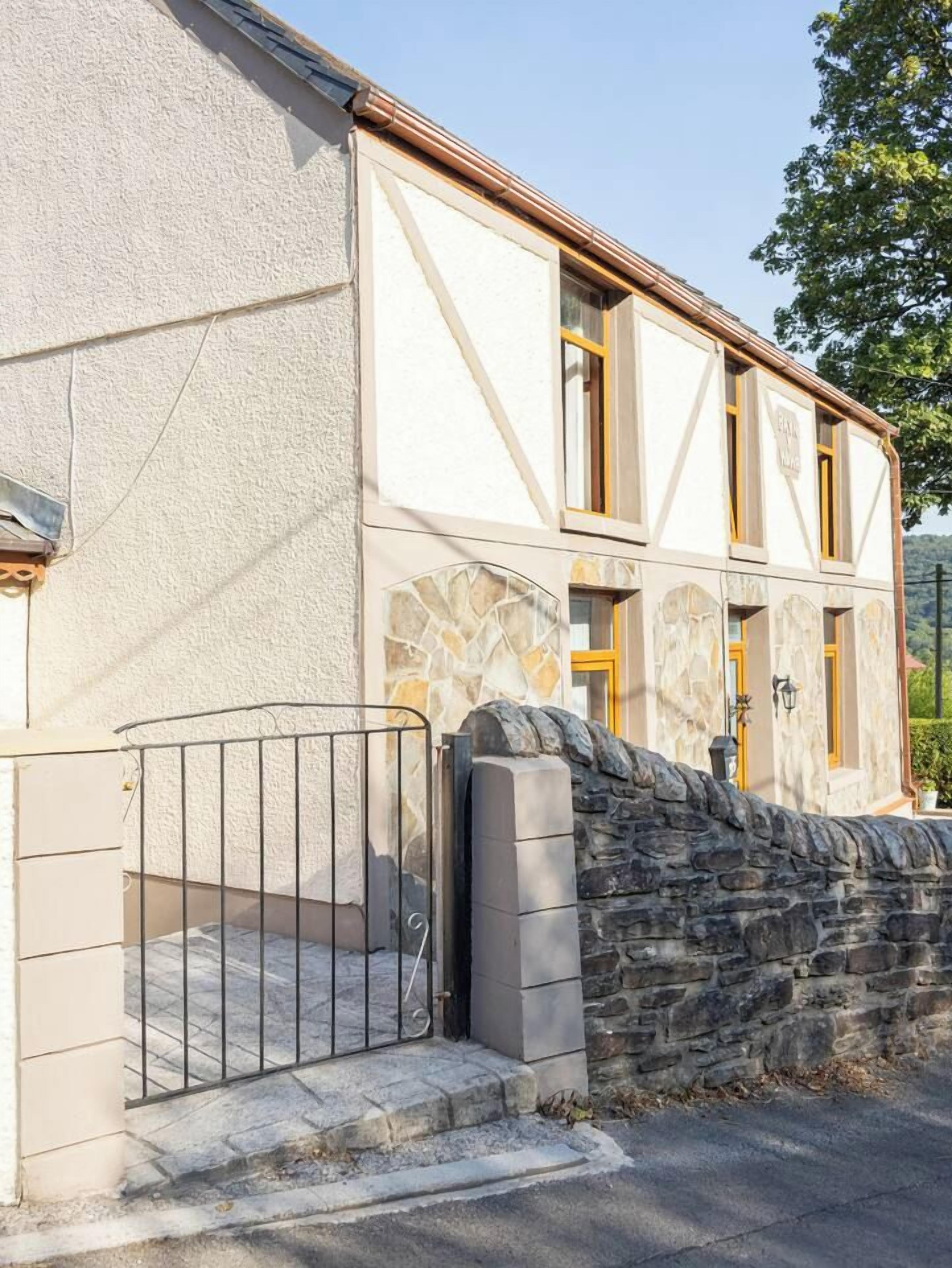 Un bâtiment doté d’une façade en pierre, d’un portail en métal et d’un mur en pierre.