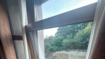 A room with a large window, a door, and a wooden floor.