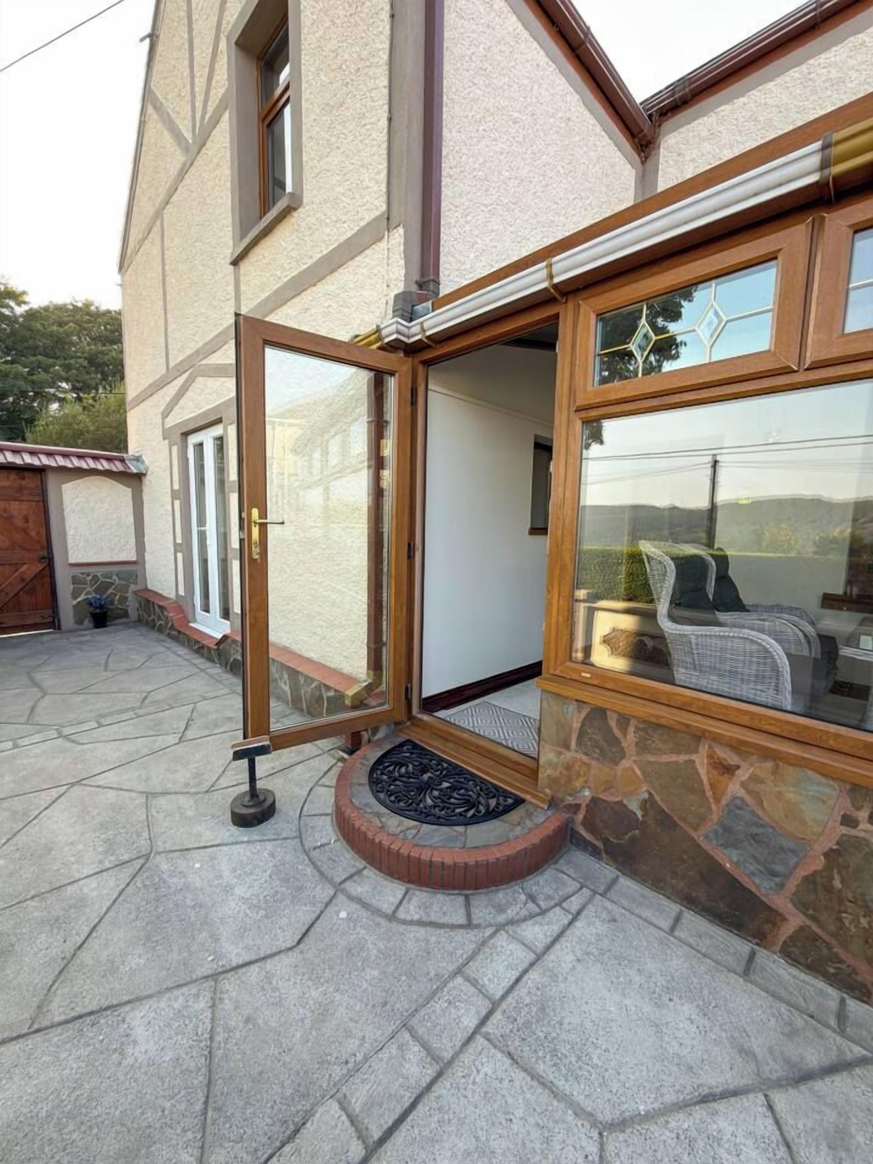 Ein Haus mit einer großen Glasdoor, die auf eine überdachte Terrasse führt.