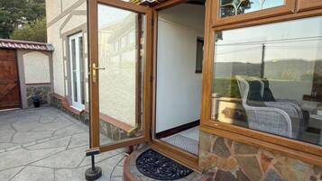 Ein Haus mit einer großen Glasdoor, die auf eine überdachte Terrasse führt.