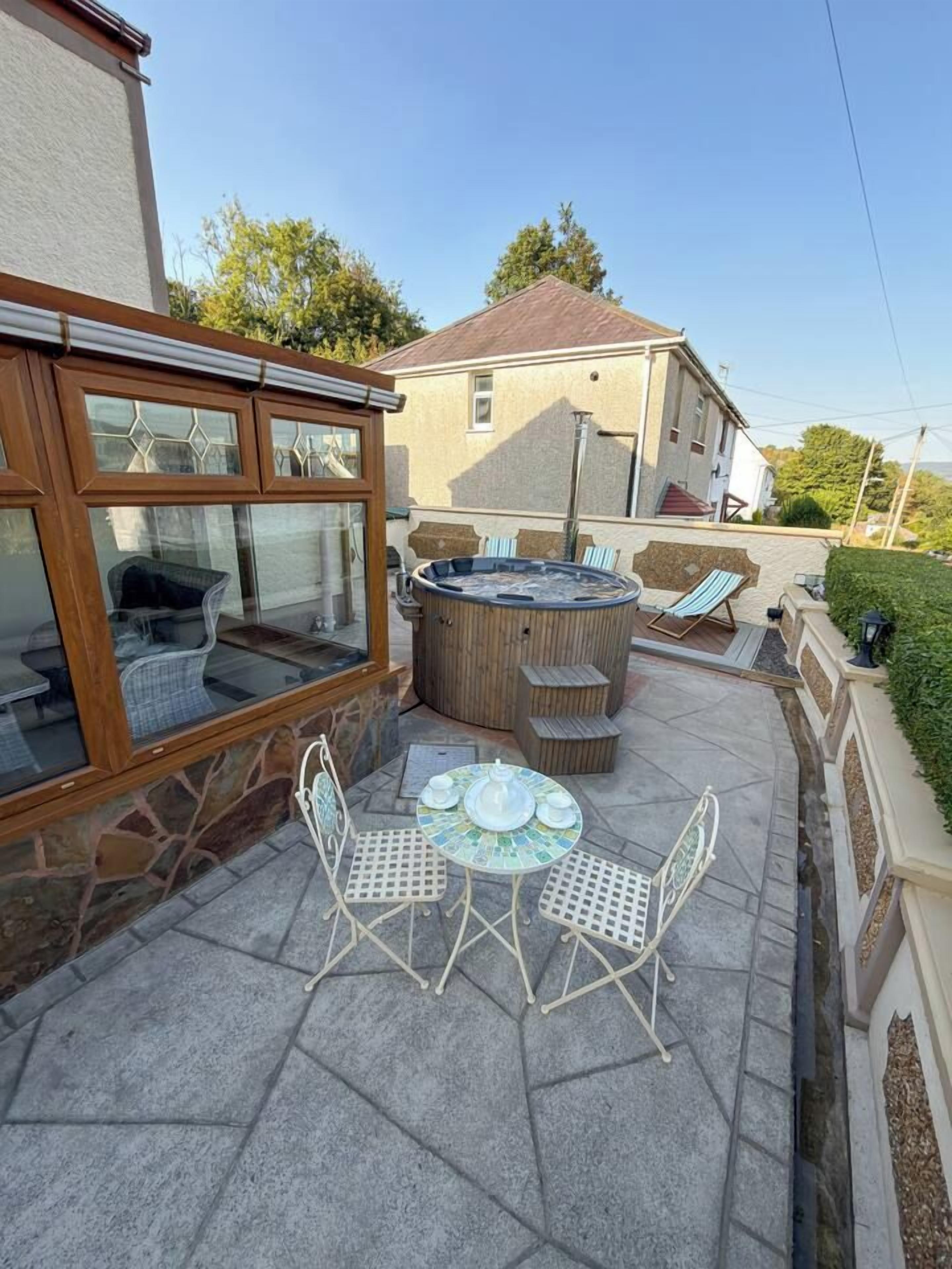Eine Terrasse mit Whirlpool, Sitzgelegenheit und Tisch.