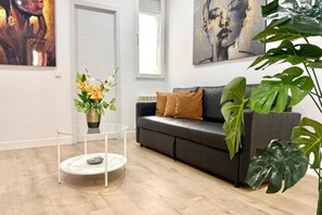 A modern living room with a leather sofa, a glass coffee table, and large green plants. - Malasaña II (Madrid)