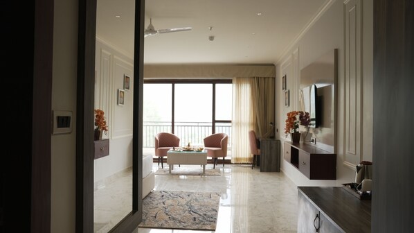 A modern living room with a large window, a flat-screen TV, and a dining area with two chairs.