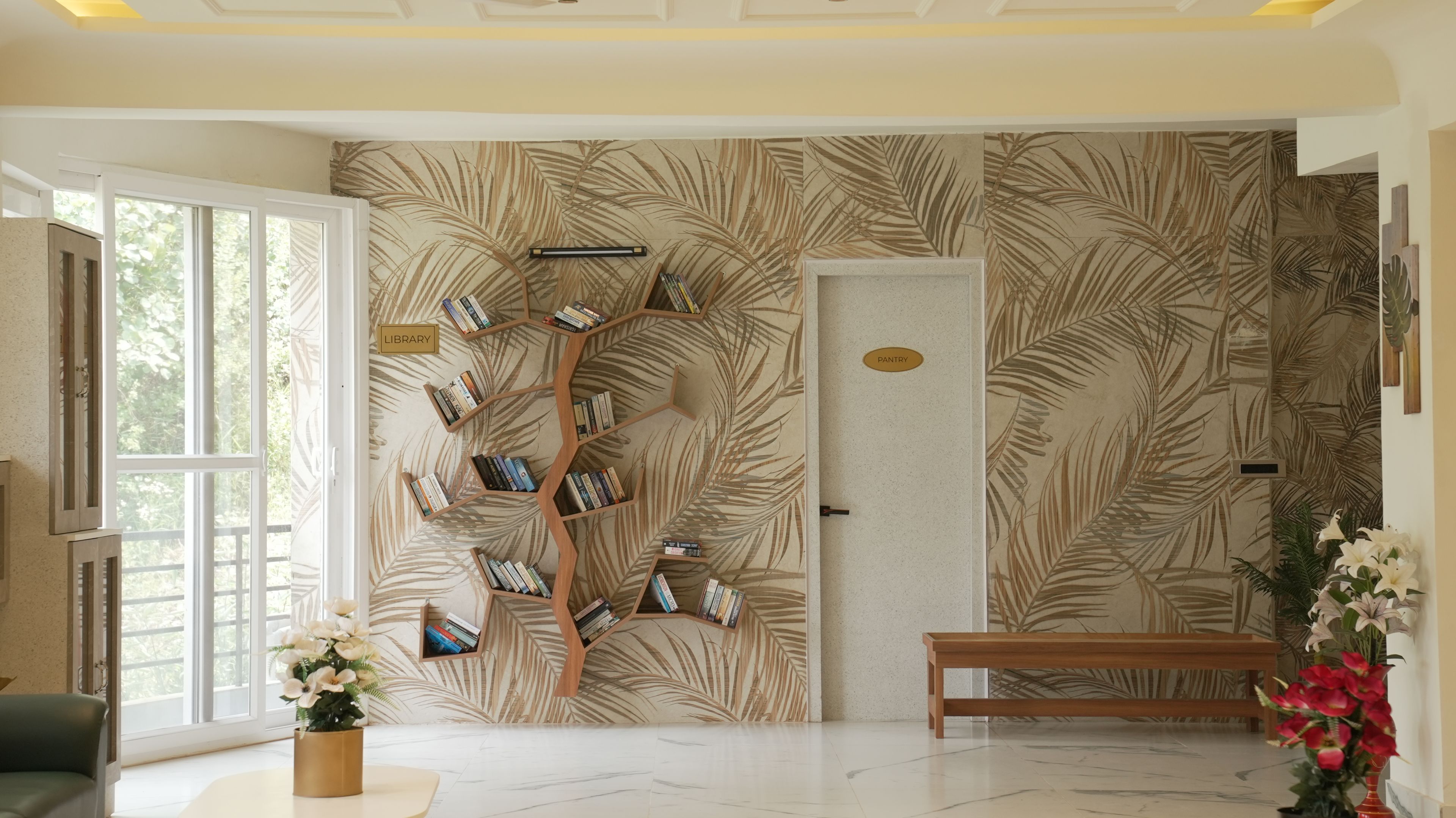 Quarto com papel de parede de folha de palmeira, estante de madeira, um banco e porta com a etiqueta 'PANTRY'.