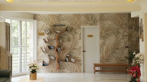 A room with a palm leaf wallpaper, a wooden bookshelf, a bench, and a door labeled 'PANTRY'.