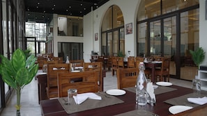A restaurant with wooden tables and chairs, large windows, and a modern interior design.