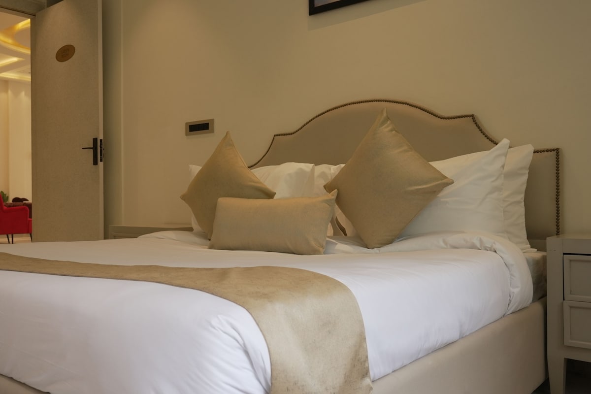 A hotel room with a large bed, beige bedding, and a red chair in the corner.