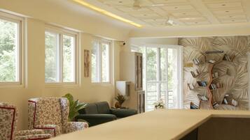 A room with large windows, a bookshelf, and a seating area.