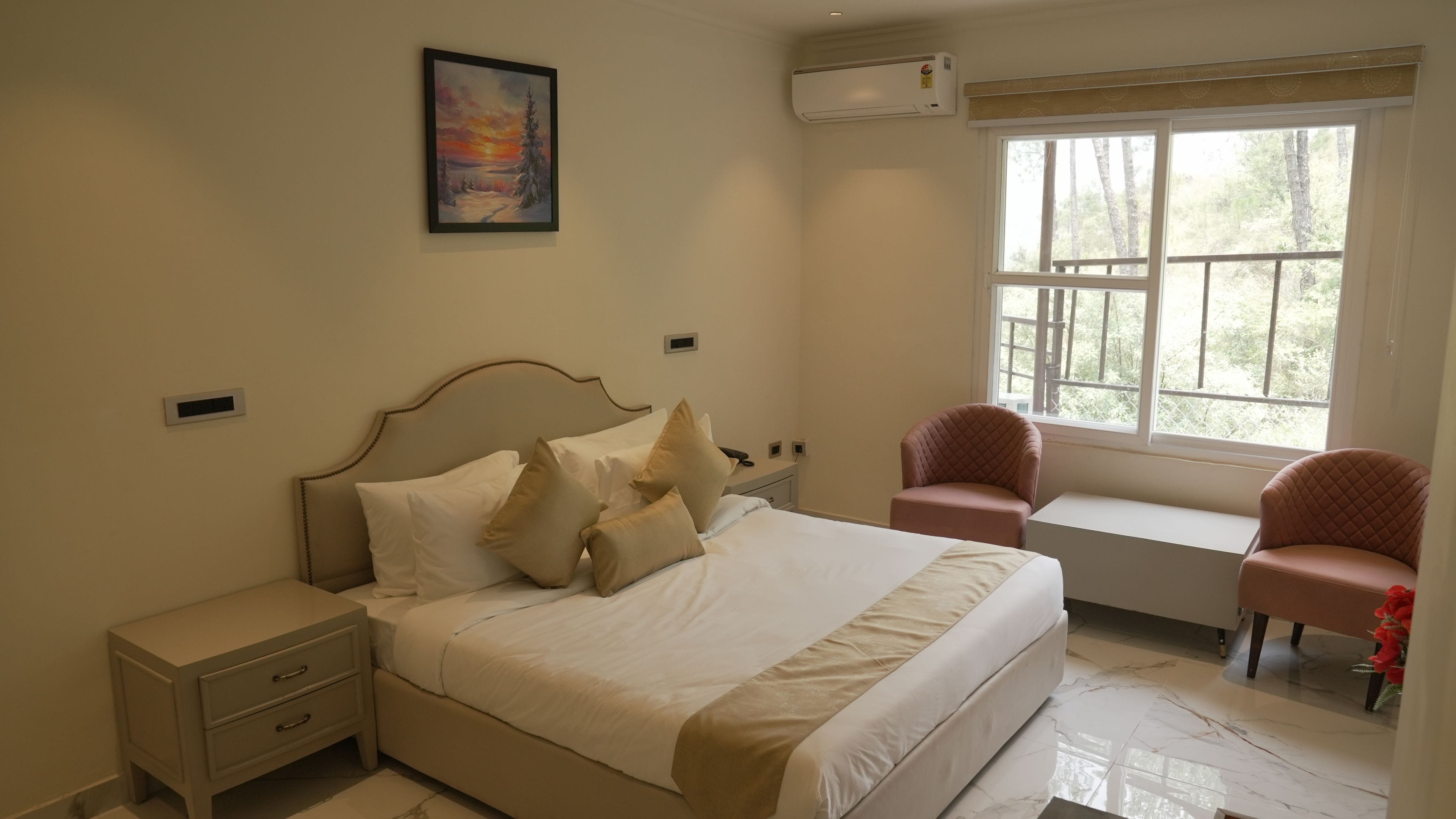 A bedroom with a bed, bedside tables, a chair, a window, and a painting on the wall.