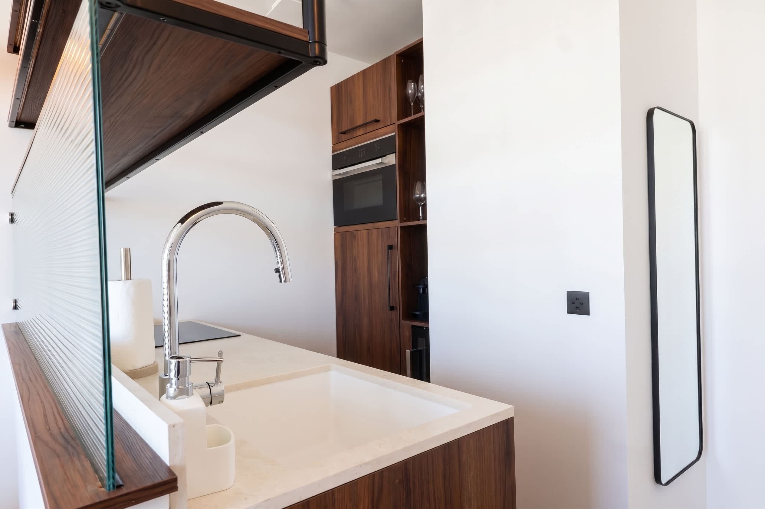 A modern bathroom with a white sink, chrome faucet, and wooden cabinets.