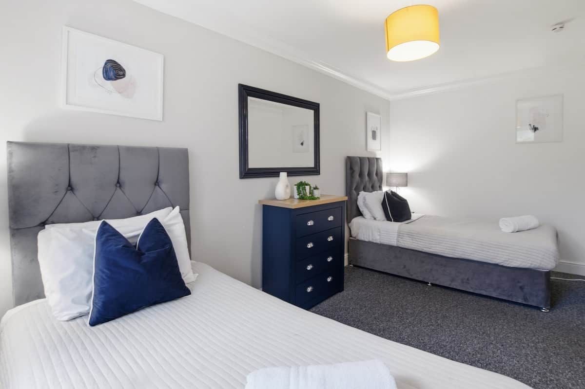 Et hotelværelse med seng, kommode, bænk og et spejl på væggen.