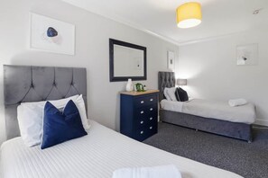Et hotelværelse med seng, kommode, bænk og et spejl på væggen.