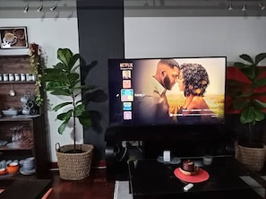 Een woonkamer met een televisiescherm waarop een selectie van Netflix-profielen wordt weergegeven.