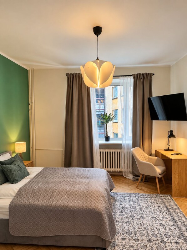 A hotel room with a bed, desk, chair, and a view of the cityscape.